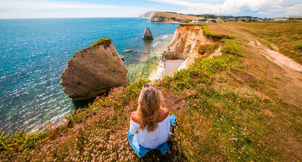 Lady sitting on cliff looking out to the sea