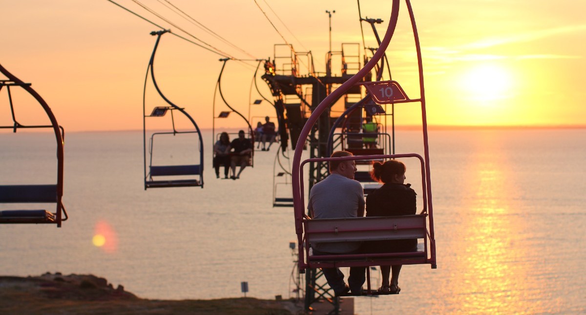 Couple riding chairlift with sunset in background