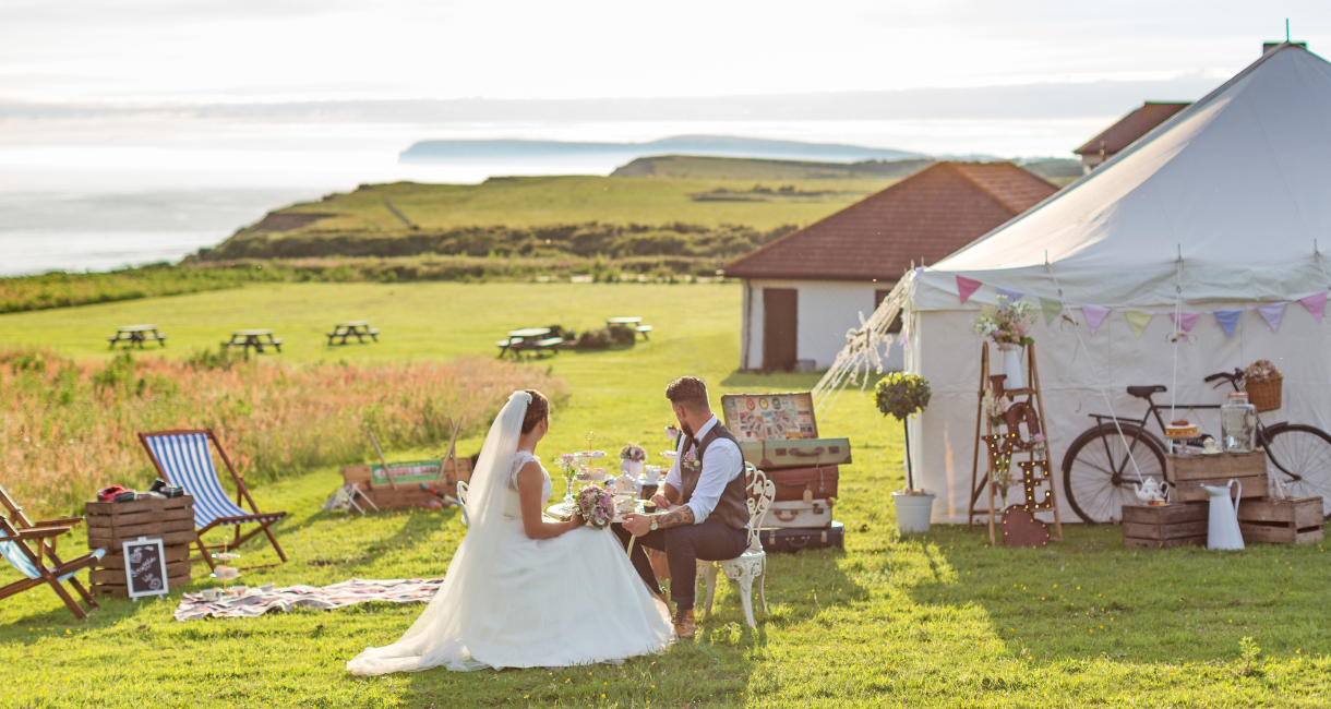 Bride and groom sitting within the grounds of Isle of Wight Pearl with sea in the background