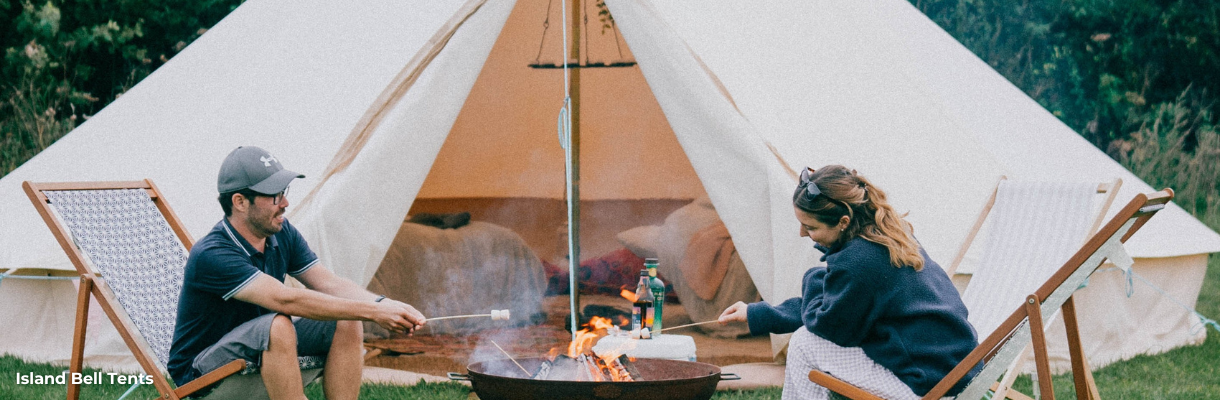 Couple roasting marshmallows over the fire outside a bell tent from Island Bell Tents on the Isle of Wight