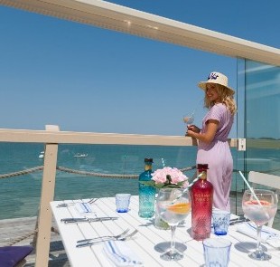 Lady enjoying drink on balcony of The Hut, Colwell