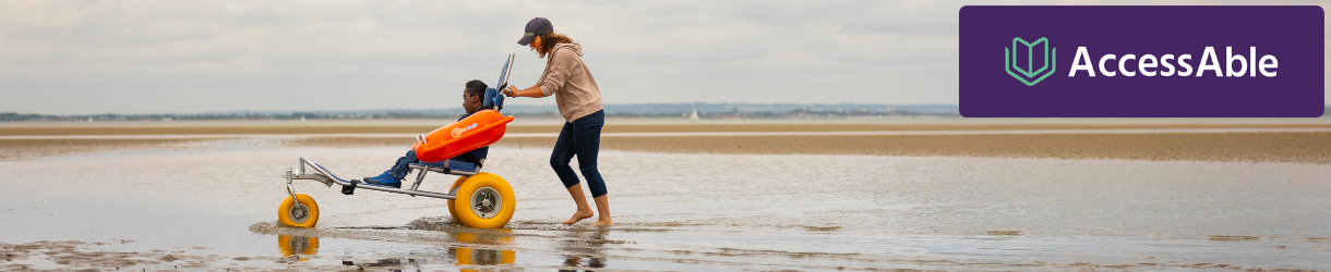 Lady pushing boy in beach wheelchair on Ryde beach on the Isle of Wight