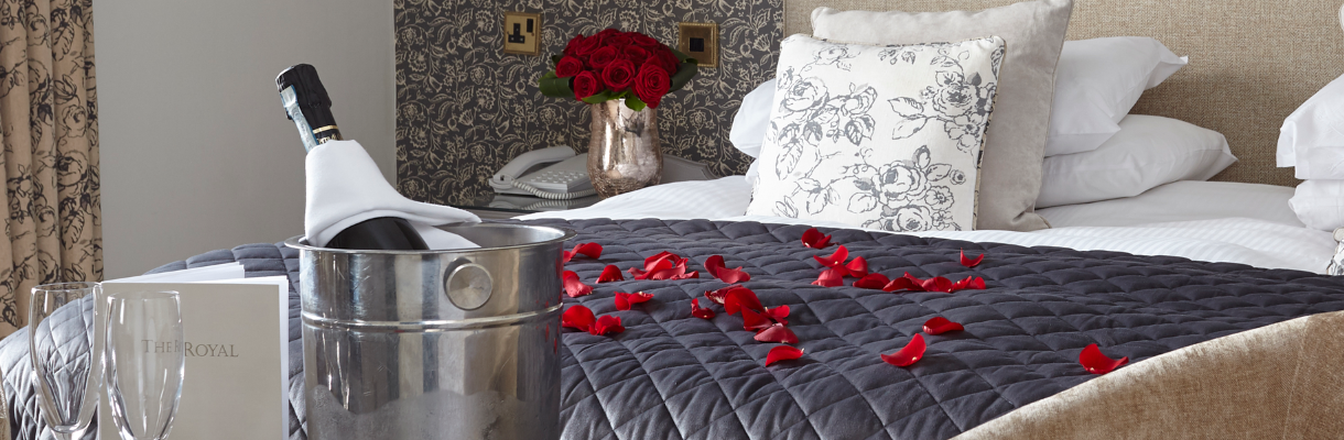 Bedroom with petals on the bed and bottle of champagne at The Royal Hotel
