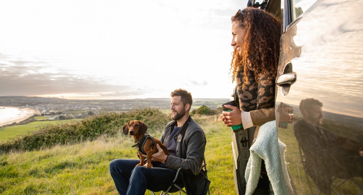 Couple and dog sitting in campervan on Culver Down