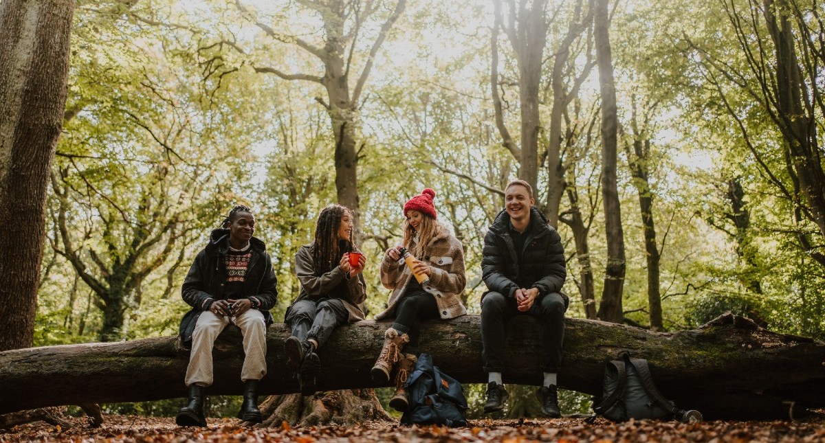 Group having drinks on a log in the forest