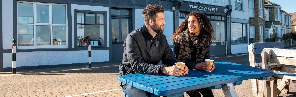 Couple drinking coffee on picnic bench